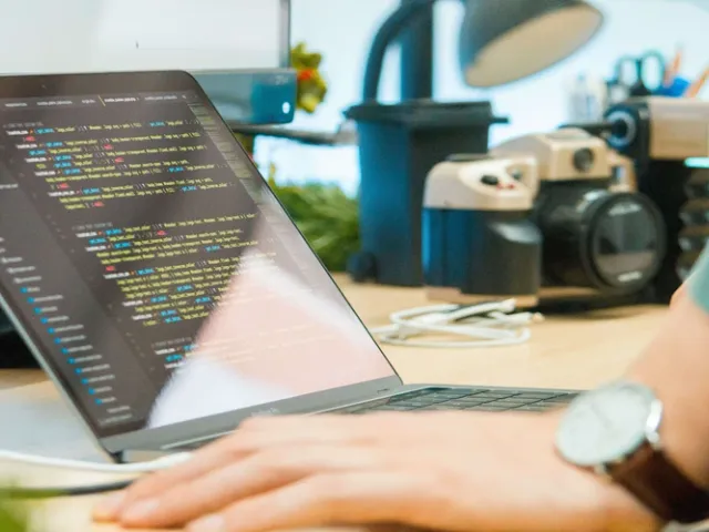 Profissional programando em notebook sobre mesa de madeira, representando o desenvolvimento de soluções com machine learning
