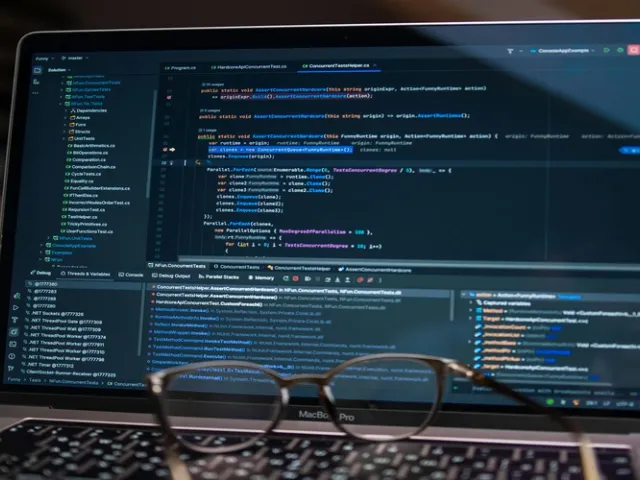 Notebook com códigos de programação ambientado em escritório de TI com óculos em cima do notebook